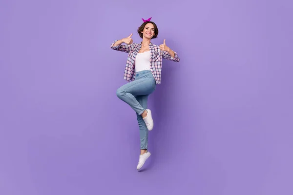 반짝이는 매력적 인 여성의 사진 체크무늬 셔츠를 입은 채 깡충깡충 뛰어오르는 모습 이 외진 자주색 배경을 보여 주고 있다 — 스톡 사진