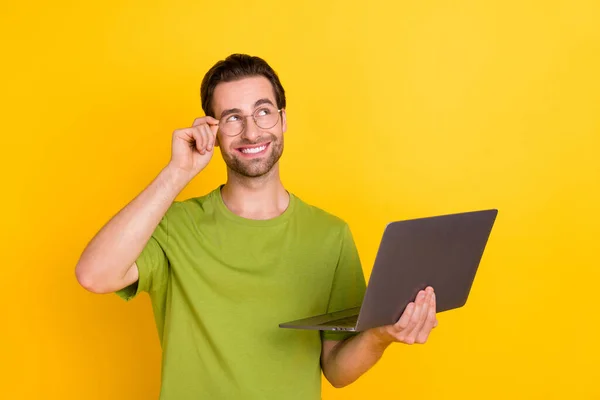 Zdjęcie funky broda młody facet trzymać laptop wygląd promo nosić okulary zielony t-shirt izolowany na żółtym tle kolor — Zdjęcie stockowe