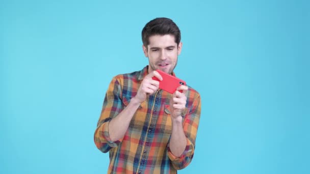 Залежний хлопець грає в кулак гаджета ізольований синій колір фону — стокове відео