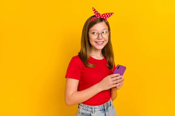 Foto de linda adorable dulce tipo pequeña dama mirar espacio vacío de navegación en el teléfono aislado en el fondo de color amarillo —  Fotos de Stock