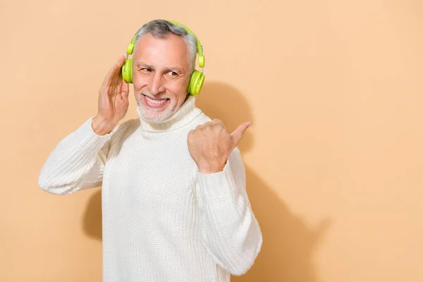 Портрет привабливого веселого модного сіро-волосистого чоловіка, який слухає поп, показує простір копіювання ізольовано на бежевому пастельному кольоровому фоні — стокове фото
