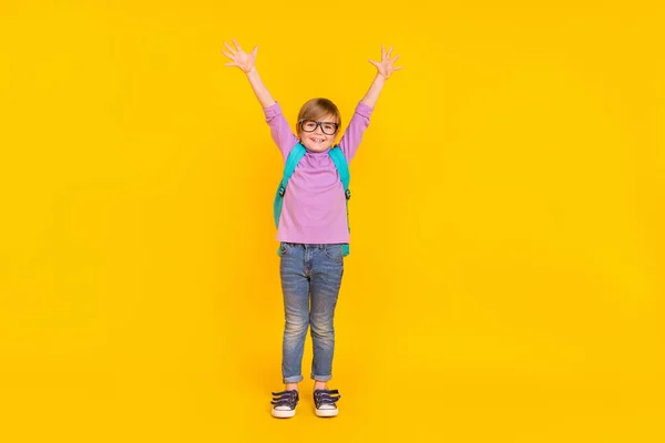 Foto em tamanho completo de bom humor engraçado aluno feliz em ir para a escola levantando as mãos em emoção isolada no fundo de cor amarela — Fotografia de Stock