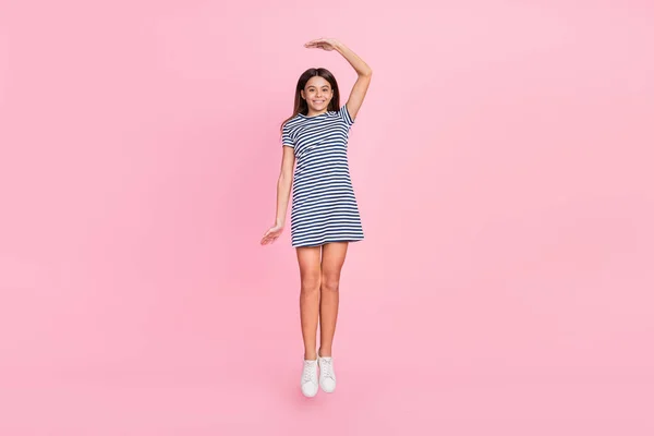 Foto av söt charmig flicka bära randig klänning hoppa hög mäthöjd isolerad rosa färg bakgrund — Stockfoto