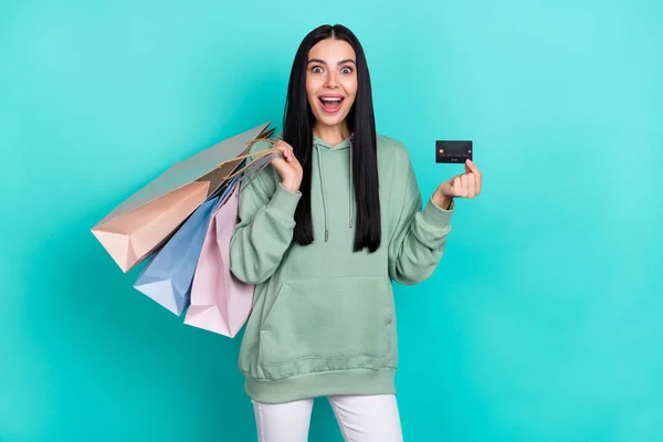 Photo of impressed young brunette lady do shopping show card wear green sweatshirt isolated on teal color background — Stock Photo, Image