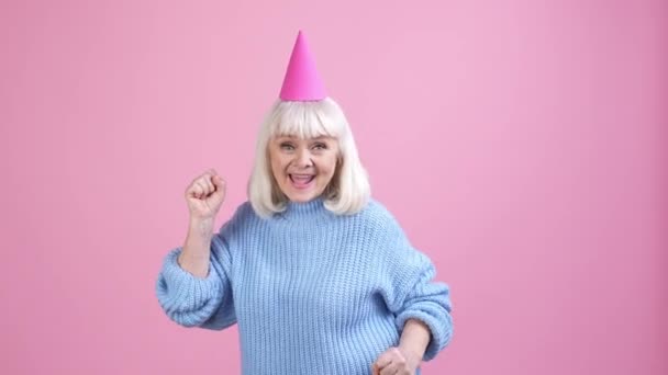 Velha senhora dança ganhar sorte presente de aniversário punho acima isolado pastel cor fundo — Vídeo de Stock