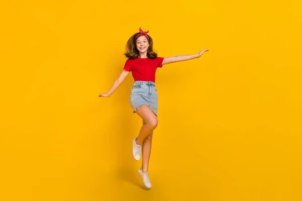 Full storlek foto av cool tonåring flicka hoppa bära röd t-shirt hårband kjol skor isolerad på gul färg bakgrund — Stockfoto