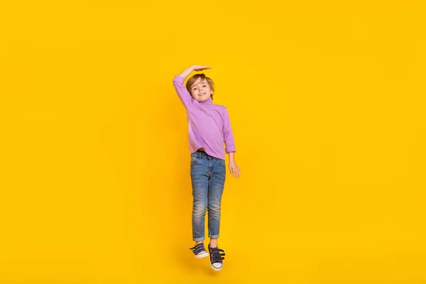 Pełny rozmiar zdjęcie wesoły cute little boy jumping marzy, aby stać się wyższy izolowany na żółtym tle kolor — Zdjęcie stockowe