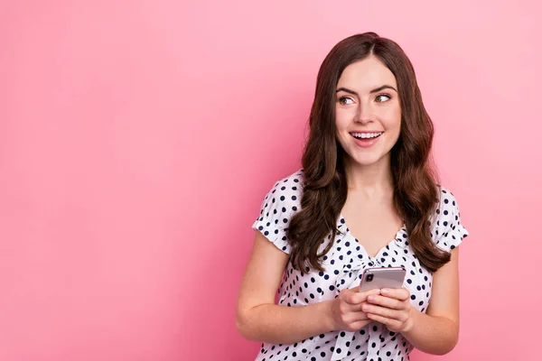Portret uroczej dziewczyny wyglądają puste miejsce zobacz reklama smartfona promo izolowane na różowym tle koloru — Zdjęcie stockowe