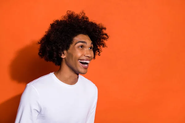 Foto del lado del perfil del chico joven riéndose humorístico mirar espacio vacío aislado sobre fondo de color naranja —  Fotos de Stock