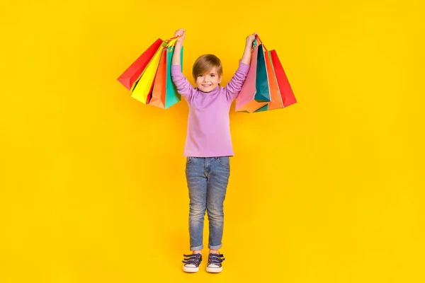 Full size foto di affascinante ragazzino andare shopping show borse comprare abiti casual isolati su sfondo di colore giallo — Foto Stock