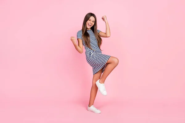 Foto van grappig gelukkig meisje dragen gestreepte jurk glimlachen lopen rijzende vuisten schreeuwen geïsoleerde roze kleur achtergrond — Stockfoto