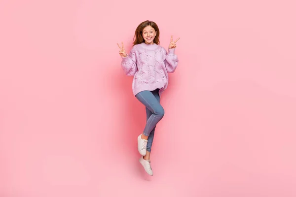 흥분 한 소녀의 뜨개 질 스웨터 높이뛰기 사진 v 사인 고립된 핑크 색 배경을 보여 주고 있다 — 스톡 사진