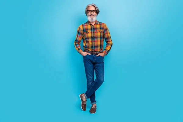 Bild av charmig attraktiv man pensionär klädd rutig skjorta glasögon armar fickor isolerad blå färg bakgrund — Stockfoto