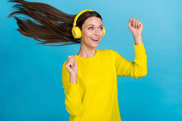 Fotografie cool milennial brunetka dáma poslouchat hudbu tanec oblečení žlutý pullover sluchátka izolované na modrém pozadí — Stock fotografie