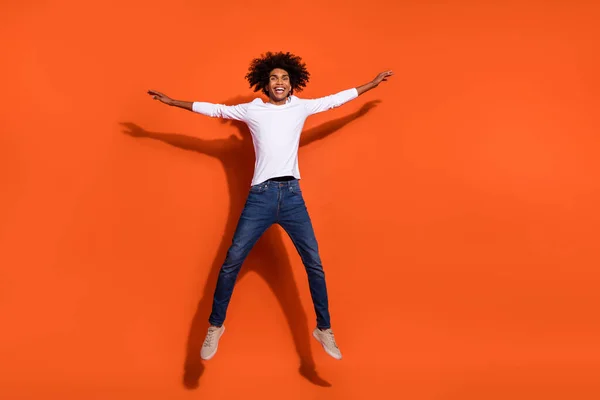 Foto de chico excitado dulce usar camisa blanca saltando alto como la estrella aislado fondo de color naranja — Foto de Stock