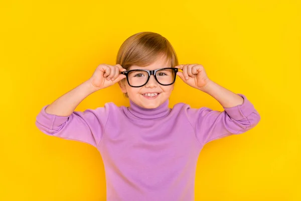 Foto de menino bonito com óculos de toque de cabelo claro ajustá-los usar gola alta violeta isolado no fundo de cor amarela — Fotografia de Stock