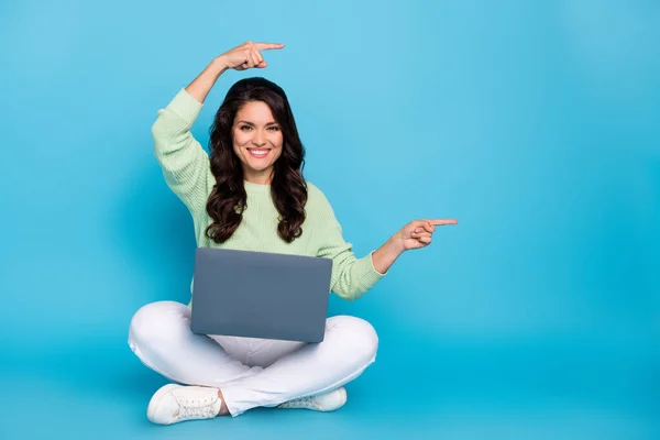 Portret atrakcyjnej wesołej kobiety siedzącej przy użyciu laptopa pokazującego ofertę miejsca na ksero na jasnoniebieskim tle — Zdjęcie stockowe