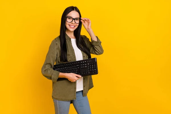 Foto de boa jovem senhora segurar keayboard usar óculos camisa cáqui isolado no fundo amarelo — Fotografia de Stock