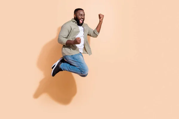 Foto de perfil de longitud completa de chico brunet joven fresco salto gritar usar camisa jeans calzado aislado sobre fondo beige — Foto de Stock