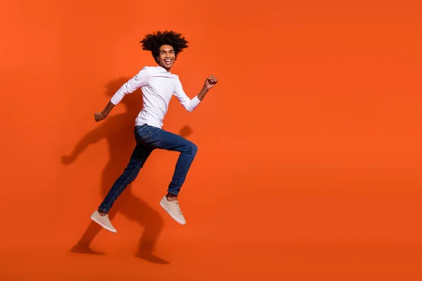 Foto de chico guay vestido camisa blanca corriendo rápido saltando alto espacio vacío aislado color naranja fondo — Foto de Stock