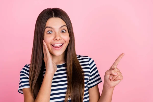 Foto di adorabile ragazza scioccata vestiti vestiti a strisce che indica vuoto spazio braccio guancia isolato colore rosa sfondo — Foto Stock