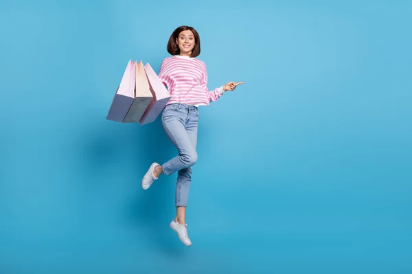 Full body photo of funny brunette millennial lady hold bags indiquer promo porter pull jeans baskets isolées sur fond bleu — Photo