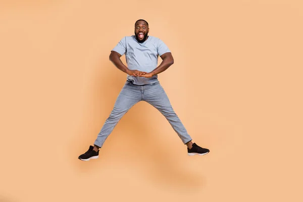 Full längd kroppsstorlek bild av attraktiv glad kille hoppa bra humör lura isolerad över beige pastell färg bakgrund — Stockfoto