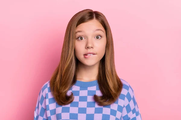 Фотографія коричневого зачіски вразила маленьку дівчинку, яка кусає губу, одягнена в синій пуловер ізольована на пастельному рожевому фоні — стокове фото