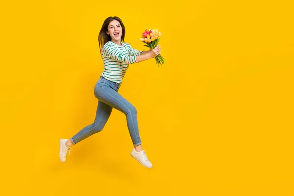 Full body foto van het lopen aantrekkelijke meisje geven mam aanwezig op verjaardag vrouw dag geïsoleerd op geel kleur achtergrond — Stockfoto