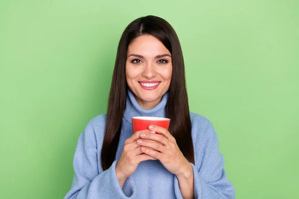 Foto de boa jovem morena senhora segurar copo desgaste pulôver azul isolado no fundo de cor verde — Fotografia de Stock