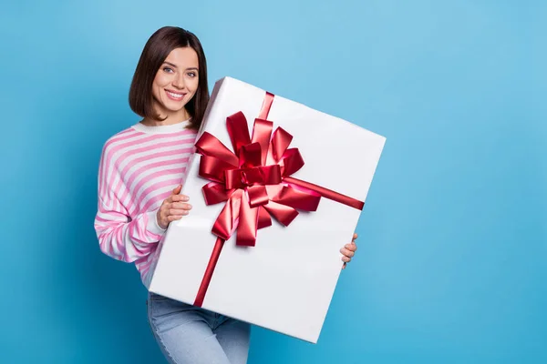 Zdjęcie słodkie młoda brunetka pani trzymać duży prezent nosić różowy sweter odizolowany na niebieskim tle — Zdjęcie stockowe