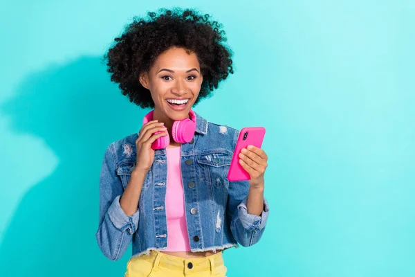 Photo of funny charming young woman wear jeans jacket headphones typing device isolated turquoise color background — Stock Photo, Image