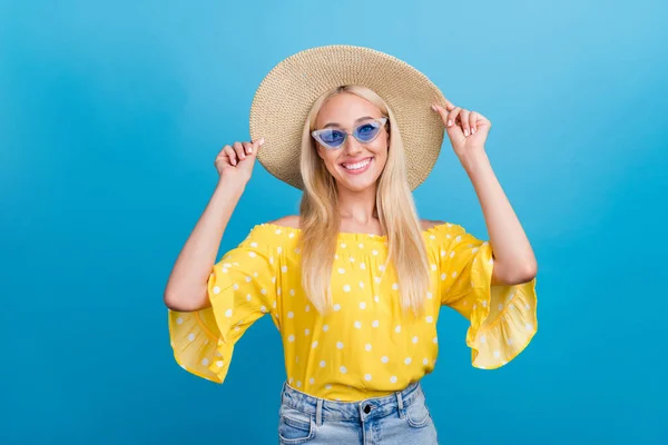 Φωτογραφία από χαριτωμένο νεαρή τολμηρή κυρία τα χέρια καπέλο φορούν κίτρινα γυαλιά κορυφή απομονώνονται σε μπλε φόντο χρώμα — Φωτογραφία Αρχείου
