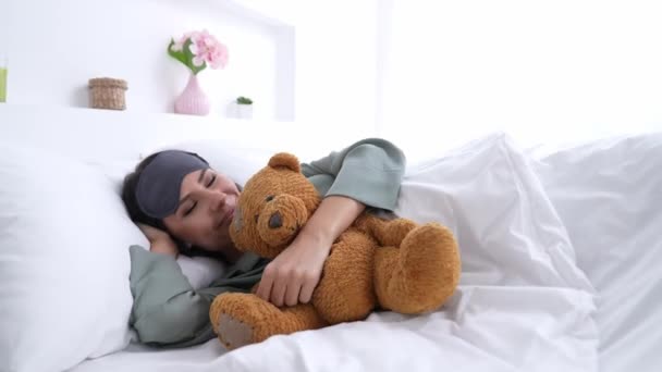 Liebenswerte Brünette wacht mit flauschigem Teddybär auf — Stockvideo