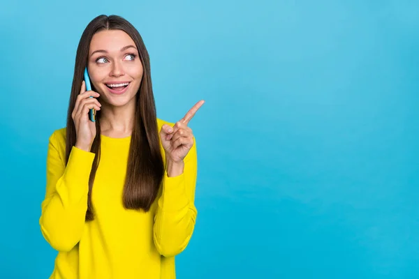 Foto de impressionado millennial morena senhora conversa telefone indicar promo desgaste camisa amarela isolada no fundo azul — Fotografia de Stock