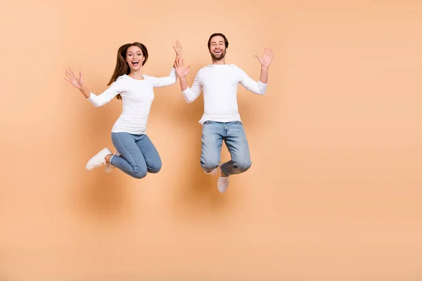 Volledige lichaamsomvang uitzicht van twee aantrekkelijke vrolijke partners springen goed humeur vakantie geïsoleerd over beige pastel kleur achtergrond — Stockfoto