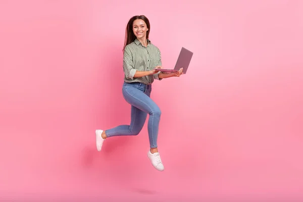 Foto corpo pieno di impressionato millenaria signora bruna eseguire con il computer portatile usura vestito jeans scarpe isolate su sfondo rosa — Foto Stock