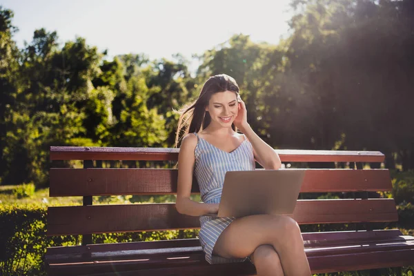 Photo de mignon positif collège étudiant fille à distance étudier en ligne dans netbook sans fil lecture document email assis banc en plein air — Photo