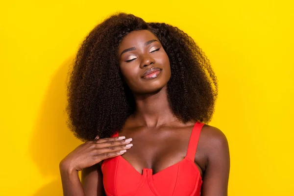 Foto de sonho brilhante senhora africana vestida vermelho sexy roupas sorridente braços peito fechado olhos isolado cor amarela fundo — Fotografia de Stock