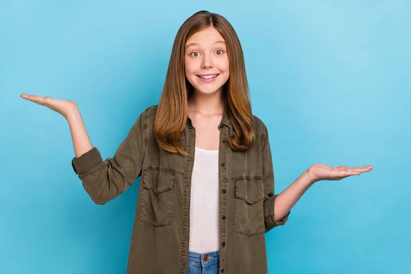 Foto de hermosa niña ropa casual camisa caqui anunciar oferta de producto alternativo aislado en fondo de color azul — Foto de Stock