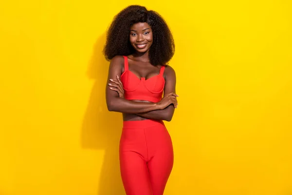 Fotografie okouzlující sladké afro dívka nosit červené sexy outfit ruce složené s úsměvem žlutá barva pozadí — Stock fotografie