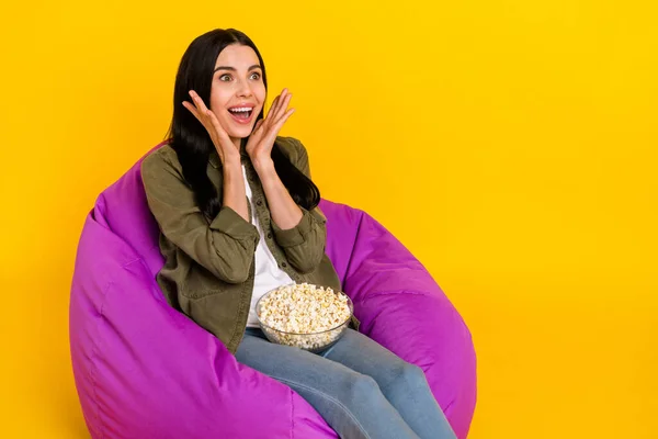 Photo of funny millennial lady look tv nosić dżinsy izolowane na żółtym tle — Zdjęcie stockowe