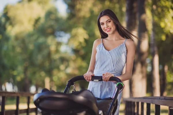 Foto de adorable buen humor joven madre viajando al aire libre con pequeño bebé recién nacido hijo empujando cochecito —  Fotos de Stock