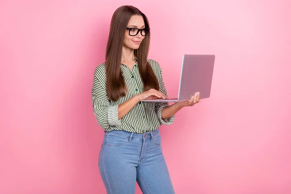Zdjęcie szefa millenium brunetka pani typ laptop nosić okulary koszula dżinsy izolowane na różowy kolor tła — Zdjęcie stockowe