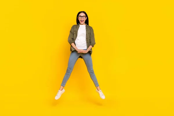 Полное фото тела прохладной женщины тысячелетия прыгать носить очки рубашку джинсы кроссовки изолированы на желтом фоне — стоковое фото