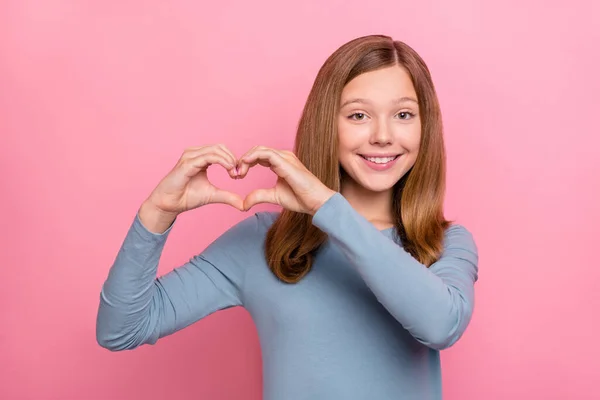 Foto de menina adolescente loira bonita mostrar coração desgaste camisa azul isolado no fundo cor-de-rosa — Fotografia de Stock