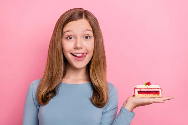 Portret van aantrekkelijke vrolijke grappig bruin-harig meisje houden taart likken lip geïsoleerd over roze pastel kleur achtergrond — Stockfoto