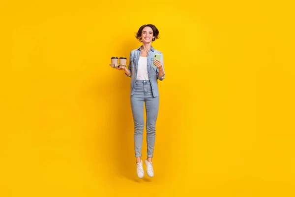 Full length φωτογραφία του νεαρού κοριτσιού άλτης χρήση smartphone κατεβάσετε app 4g latte απομονώνονται σε κίτρινο χρώμα φόντο — Φωτογραφία Αρχείου