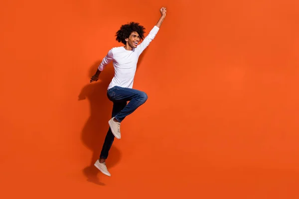 Foto de chico bastante fresco vestido camisa blanca saltando alto buscando espacio vacío aislado color naranja fondo — Foto de Stock