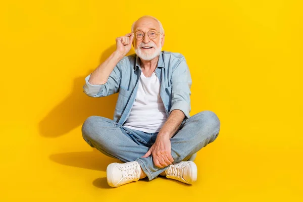 Porträtt av attraktiv säker smart smart smart glad gråhårig man sitter vidröra specifikationer isolerade över ljusa gula färg bakgrund — Stockfoto